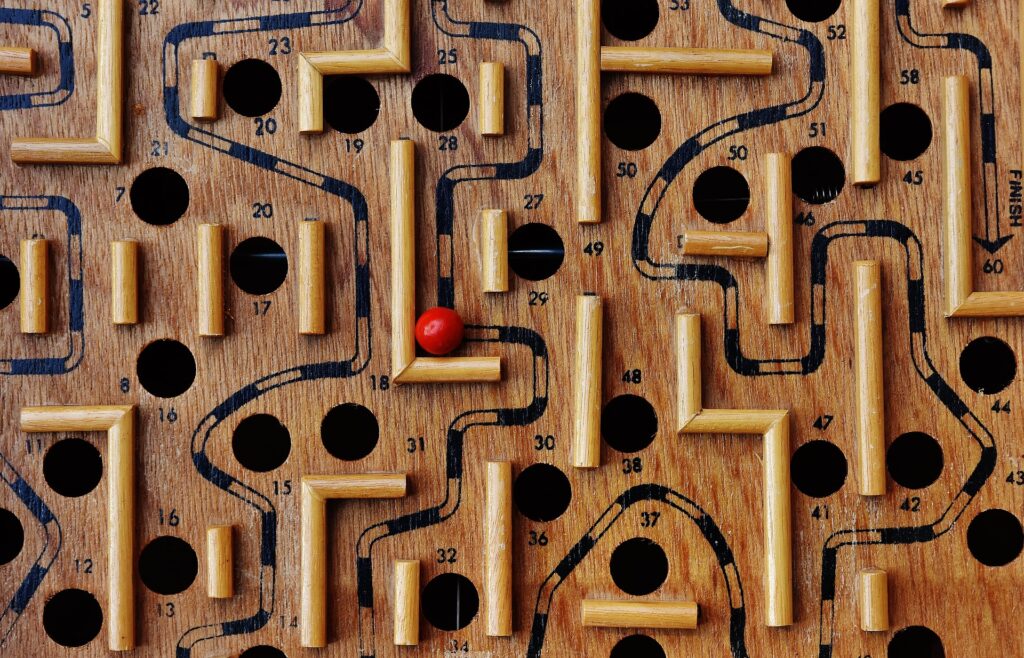 Holz-Labyrinth-Kugelspiel. Eine Kugel muss in dem Labyrinth an Löchern vorbei zum Ziel manövriert werden.