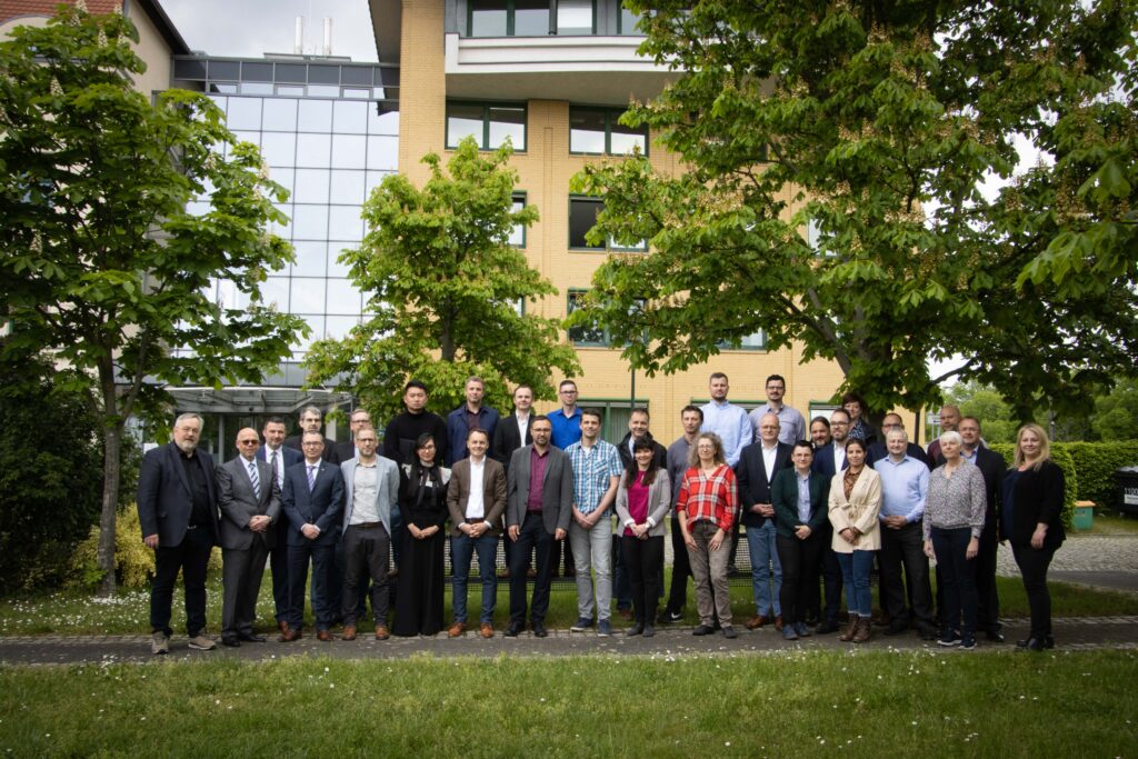 Präsenztreffen im Rahmen des CIO-Projektes. Gruppenfoto von etwa 35 Personen im Grünen vor einem größeren Gebäude. 