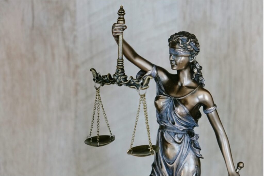 Metallene Statue von Justitia, der Göttin der Gerechtigkeit. Sie hat die Augen verbunden und hält in der einen Hand eine Waage und in der anderen ein Schwert.